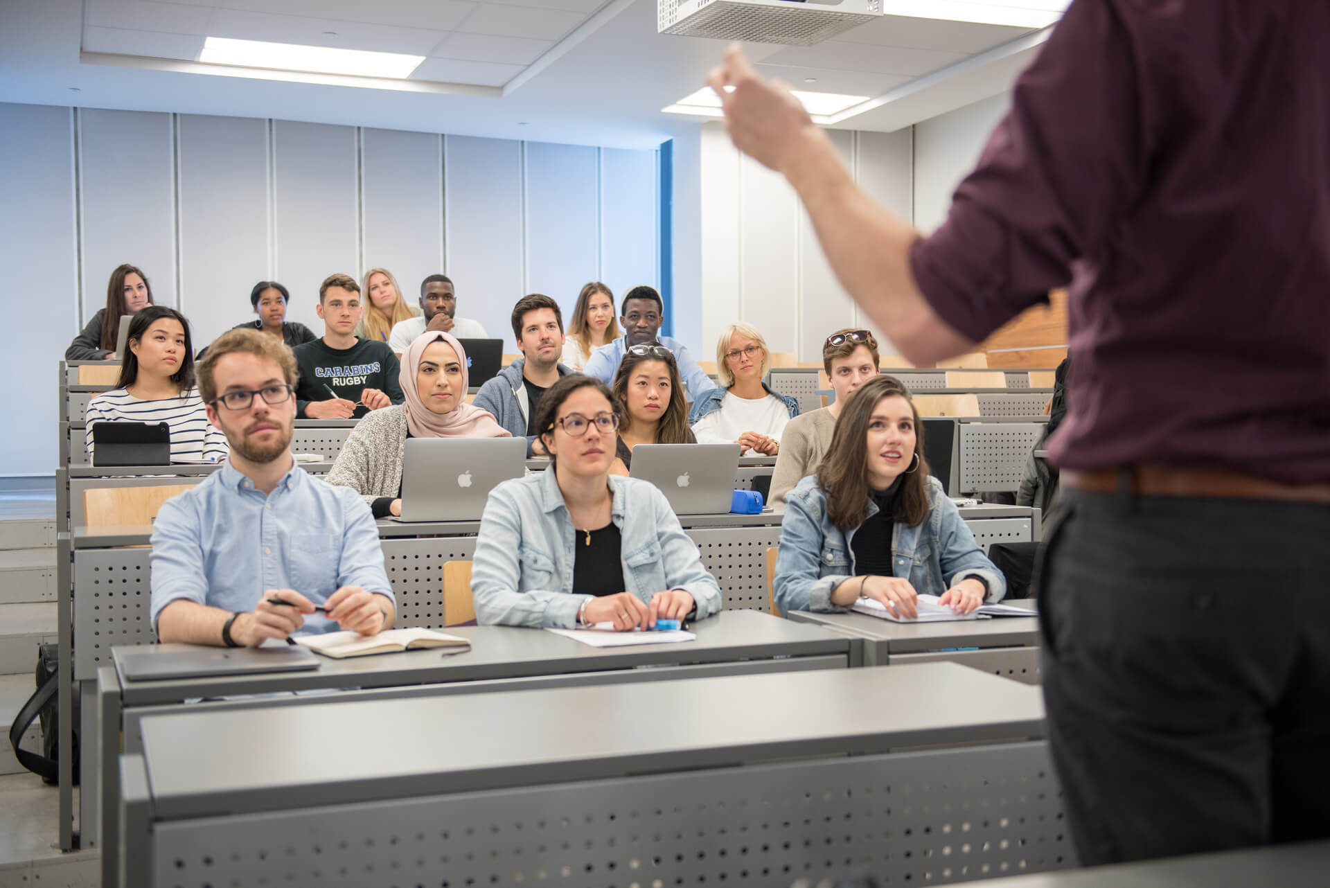 Photo d'étudiants dans un amphithéâtre écoutants un professeur